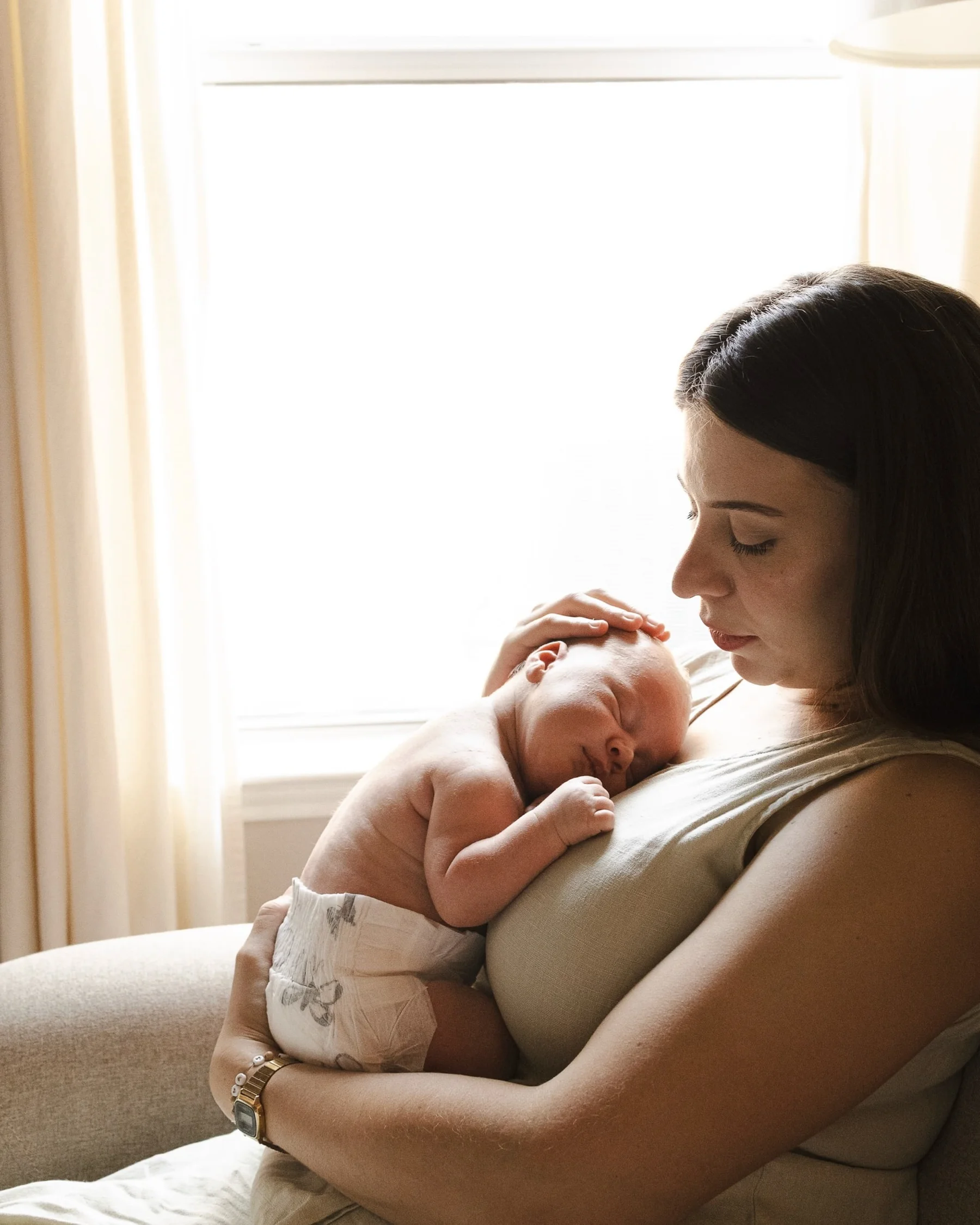 Mother holding her newborn baby in soft window light